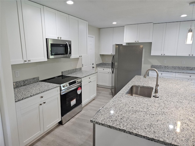 11210 Mcmullen Rd, Riverview, FL 33569 - kitchen with appliances with stainless steel finishes, white cabinetry, light wood-type flooring, recessed lighting, and light stone countertops