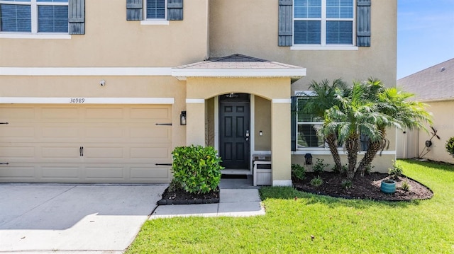 30989 Summer Sun Loop, Wesley Chapel, FL 33545 - property entrance with stucco siding, a yard, an attached garage, and driveway