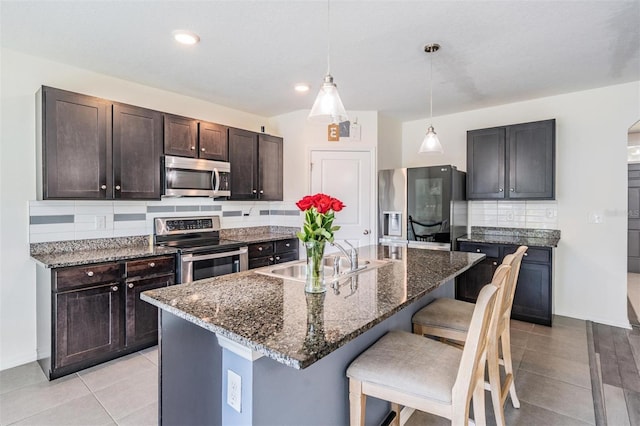 30989 Summer Sun Loop, Wesley Chapel, FL 33545 - kitchen featuring stainless steel appliances, a sink, a kitchen bar, tasteful backsplash, and dark brown cabinets