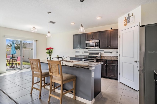 30989 Summer Sun Loop, Wesley Chapel, FL 33545 - kitchen featuring stainless steel appliances, a sink, backsplash, light tile patterned floors, and dark stone countertops