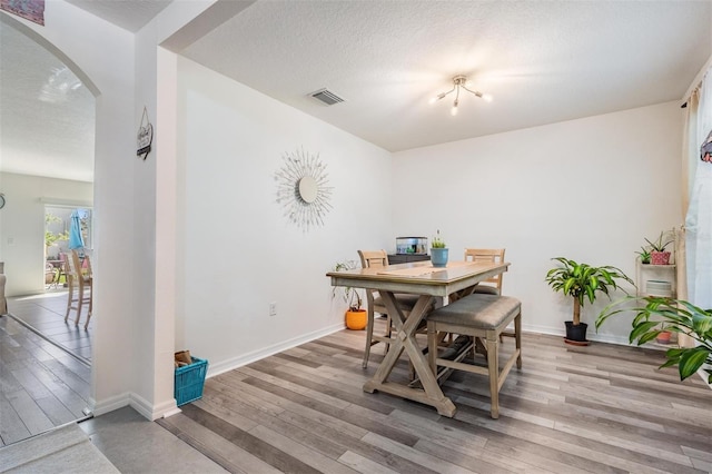 30989 Summer Sun Loop, Wesley Chapel, FL 33545 - dining space with arched walkways, wood finished floors, baseboards, and a textured ceiling
