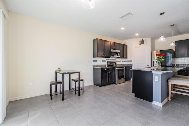 30989 Summer Sun Loop, Wesley Chapel, FL 33545 - kitchen with stainless steel appliances, backsplash, a kitchen bar, light tile patterned flooring, and recessed lighting