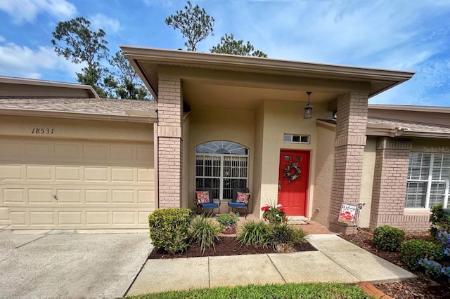 18531 Bent Pine Dr, Hudson, FL 34667 - view of exterior entry with brick siding, an attached garage, stucco siding, and driveway