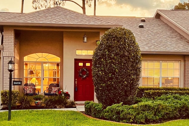 18531 Bent Pine Dr, Hudson, FL 34667 - entrance to property featuring a shingled roof, brick siding, and stucco siding