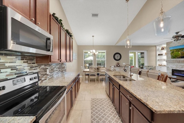 11904 Greenchop Pl, Riverview, FL 33579 - kitchen featuring appliances with stainless steel finishes, a sink, a stone fireplace, decorative backsplash, and light stone counters
