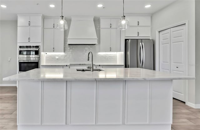 1402 Harbour Walk Rd, Tampa, FL 33602 - kitchen featuring appliances with stainless steel finishes, custom range hood, white cabinetry, recessed lighting, and a kitchen island with sink