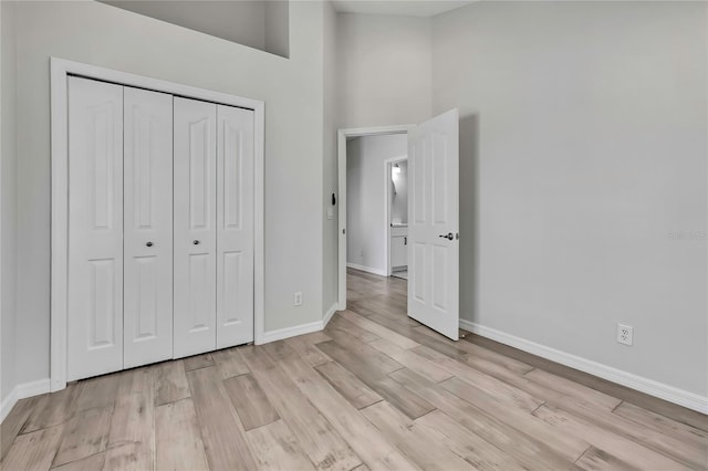 1402 Harbour Walk Rd, Tampa, FL 33602 - unfurnished bedroom featuring light wood-type flooring, baseboards, a closet, and a high ceiling