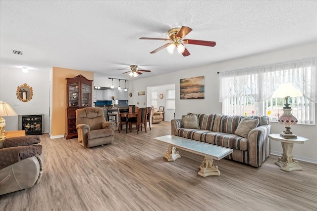 2214 Highclere Cir Unit 6, Sun City Center, FL 33573 - living area with light wood finished floors, a ceiling fan, a textured ceiling, and baseboards