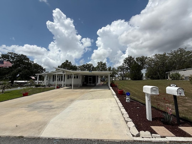 12021 Club House Rd, Brooksville, FL 34613 - manufactured / mobile home with concrete driveway, a front lawn, an attached carport, and covered porch