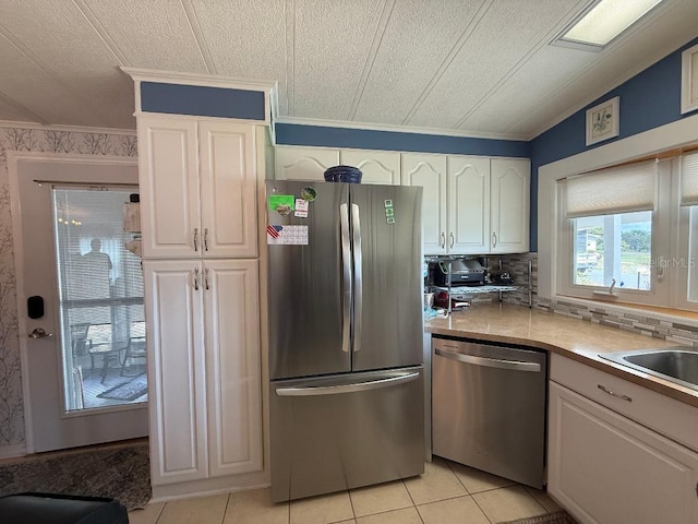 12021 Club House Rd, Brooksville, FL 34613 - kitchen featuring appliances with stainless steel finishes, white cabinets, light tile patterned floors, ornamental molding, and light countertops