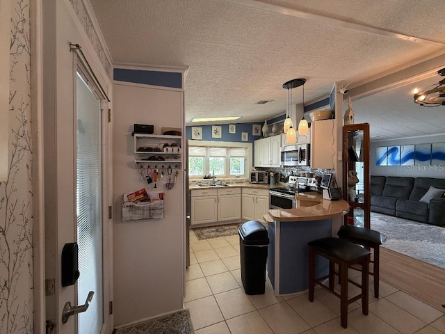 12021 Club House Rd, Brooksville, FL 34613 - kitchen with appliances with stainless steel finishes, a sink, a peninsula, a breakfast bar, and a textured ceiling