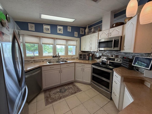 12021 Club House Rd, Brooksville, FL 34613 - kitchen featuring appliances with stainless steel finishes, a sink, backsplash, white cabinets, and light tile patterned flooring