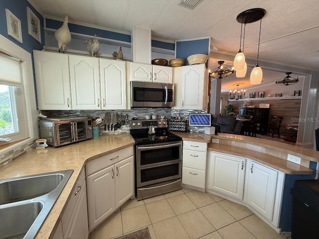 12021 Club House Rd, Brooksville, FL 34613 - kitchen featuring appliances with stainless steel finishes, a peninsula, white cabinets, decorative backsplash, and light tile patterned flooring