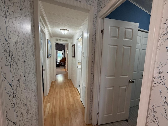 12021 Club House Rd, Brooksville, FL 34613 - hallway featuring ornamental molding, light wood-style floors, wallpapered walls, and a textured ceiling