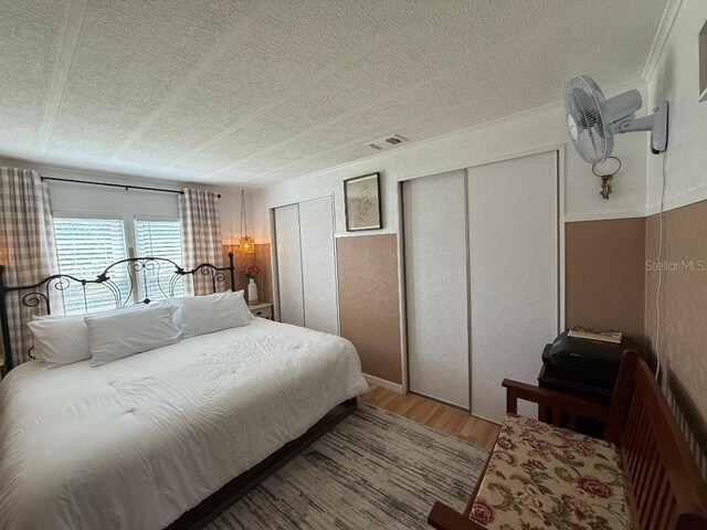 12021 Club House Rd, Brooksville, FL 34613 - bedroom featuring light wood-style floors, a textured ceiling, and two closets