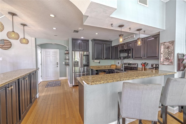 1807 Split Fork Dr, Oldsmar, FL 34677 - kitchen with stainless steel appliances, arched walkways, a peninsula, baseboards, and light wood finished floors