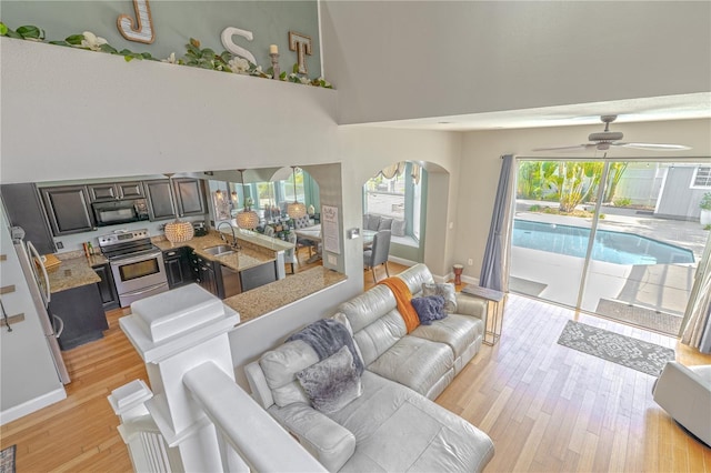 1807 Split Fork Dr, Oldsmar, FL 34677 - living area featuring ceiling fan, light wood-style flooring, arched walkways, baseboards, and a high ceiling