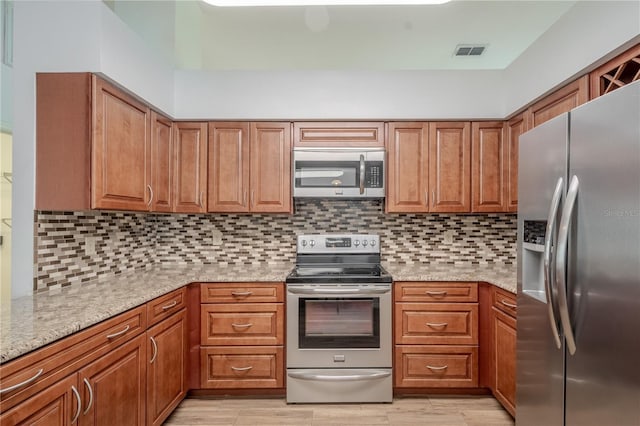 1838 Eagle Ridge Blvd, Palm Harbor, FL 34685 - kitchen featuring appliances with stainless steel finishes, brown cabinetry, and light stone counters