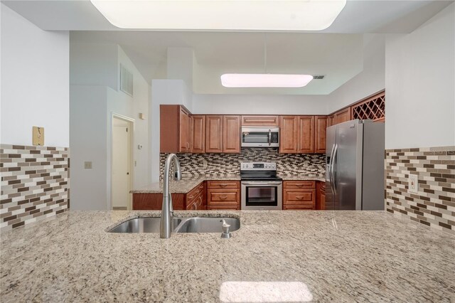 1838 Eagle Ridge Blvd, Palm Harbor, FL 34685 - kitchen with appliances with stainless steel finishes, brown cabinetry, backsplash, and light stone countertops