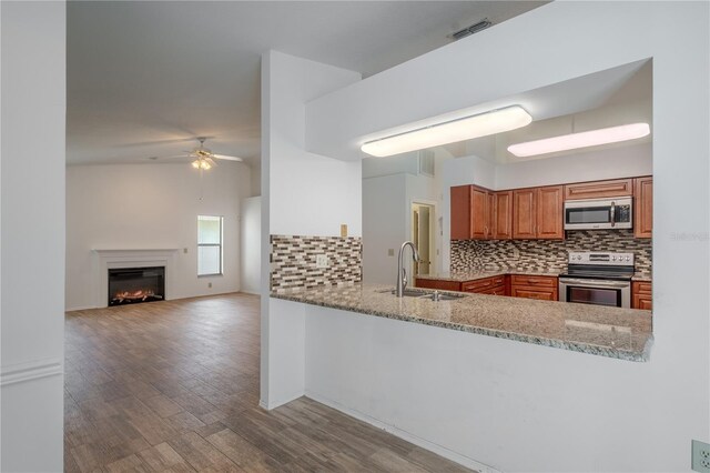 1838 Eagle Ridge Blvd, Palm Harbor, FL 34685 - kitchen featuring appliances with stainless steel finishes, backsplash, a ceiling fan, light stone countertops, and wood finished floors