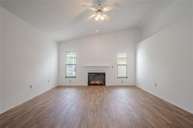 1838 Eagle Ridge Blvd, Palm Harbor, FL 34685 - unfurnished living room featuring wood finished floors, a lit fireplace, ceiling fan, and high vaulted ceiling