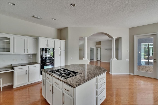 27440 Cedar Park Ct, Wesley Chapel, FL 33544 - kitchen featuring decorative columns, gas cooktop, light wood finished floors, tasteful backsplash, and dark stone counters