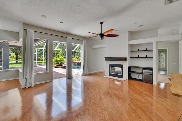 27440 Cedar Park Ct, Wesley Chapel, FL 33544 - unfurnished living room featuring a textured ceiling, a multi sided fireplace, baseboards, and wood finished floors