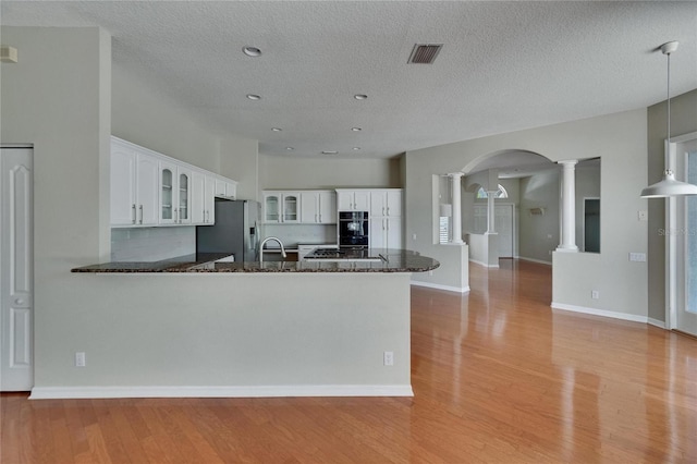 27440 Cedar Park Ct, Wesley Chapel, FL 33544 - kitchen featuring stainless steel fridge, decorative columns, black oven, glass insert cabinets, and a peninsula