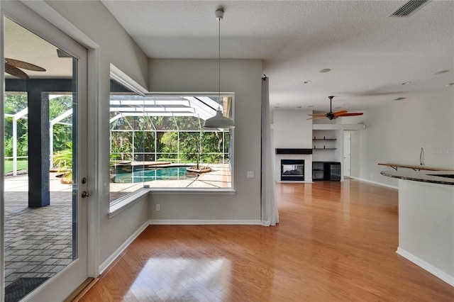 27440 Cedar Park Ct, Wesley Chapel, FL 33544 - interior space with a ceiling fan, wood finished floors, a textured ceiling, healthy amount of natural light, and a multi sided fireplace