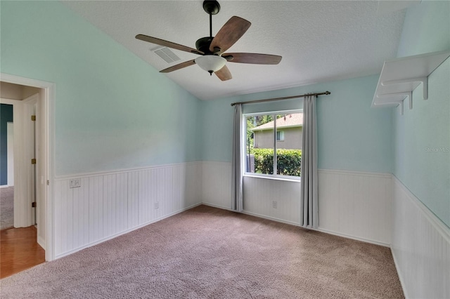 27440 Cedar Park Ct, Wesley Chapel, FL 33544 - empty room with wainscoting, ceiling fan, carpet, vaulted ceiling, and a textured ceiling