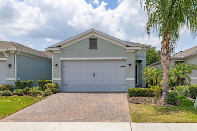 1890 Flora Pass Pl, Kissimmee, FL 34747 - ranch-style house with stucco siding, decorative driveway, and a garage