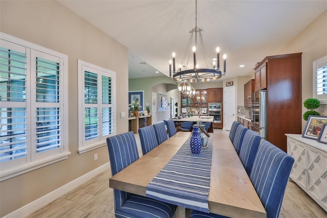 6016 Shadowlake Dr, Apollo Beach, FL 33572 - dining area featuring a chandelier, light wood-type flooring, baseboards, arched walkways, and recessed lighting
