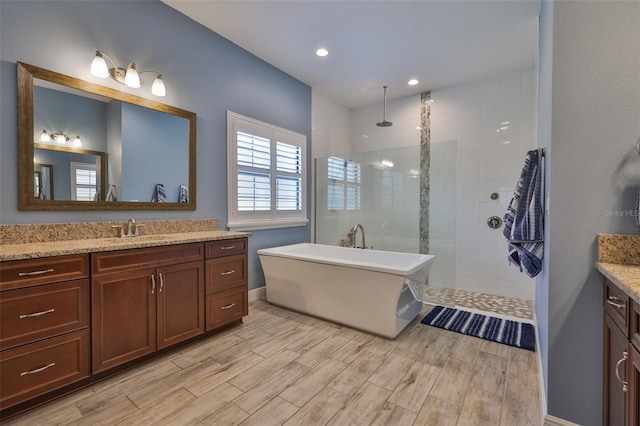 6016 Shadowlake Dr, Apollo Beach, FL 33572 - bathroom with vanity, wood finished floors, walk in shower, a freestanding bath, and recessed lighting