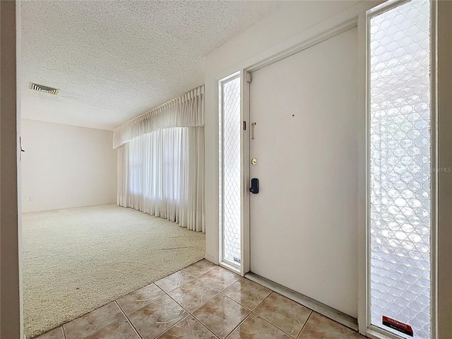 13725 Oak Forest Blvd N, Seminole, FL 33776 - entrance foyer featuring light carpet, light tile patterned floors, a textured ceiling, and plenty of natural light