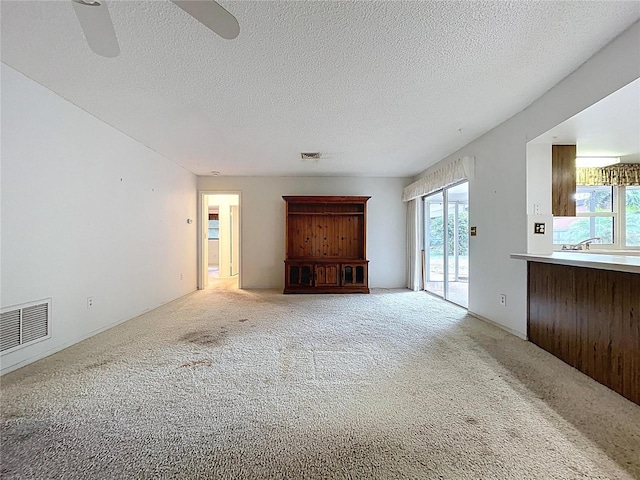 13725 Oak Forest Blvd N, Seminole, FL 33776 - unfurnished living room featuring carpet, plenty of natural light, a textured ceiling, and ceiling fan