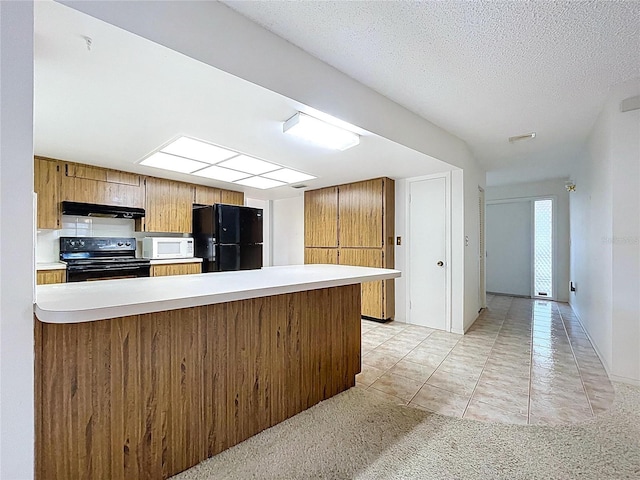 13725 Oak Forest Blvd N, Seminole, FL 33776 - kitchen with black appliances, under cabinet range hood, a peninsula, light countertops, and brown cabinetry