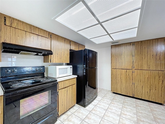 13725 Oak Forest Blvd N, Seminole, FL 33776 - kitchen featuring black appliances, under cabinet range hood, light countertops, light tile patterned flooring, and backsplash