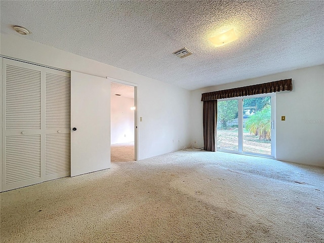 13725 Oak Forest Blvd N, Seminole, FL 33776 - unfurnished bedroom featuring carpet floors, access to exterior, a textured ceiling, and a closet