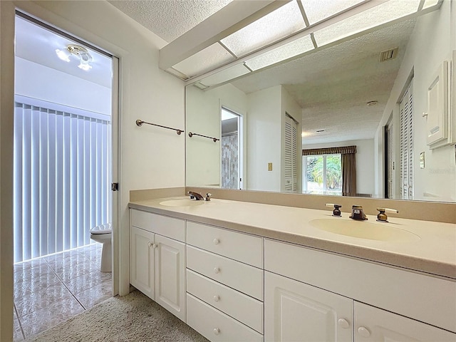 13725 Oak Forest Blvd N, Seminole, FL 33776 - full bathroom featuring double vanity, a textured ceiling, and toilet
