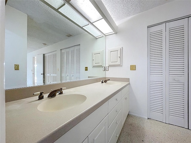 13725 Oak Forest Blvd N, Seminole, FL 33776 - bathroom featuring a closet, a textured ceiling, double vanity, speckled floor, and baseboards