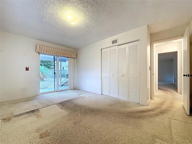 13725 Oak Forest Blvd N, Seminole, FL 33776 - unfurnished bedroom featuring carpet, access to exterior, a closet, and a textured ceiling