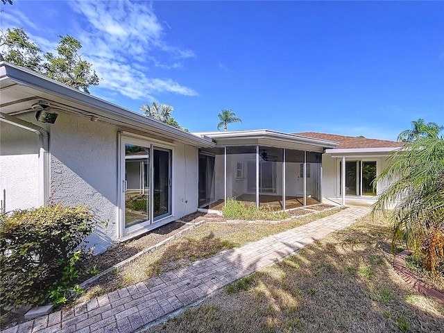 13725 Oak Forest Blvd N, Seminole, FL 33776 - back of house featuring a sunroom, stucco siding, and a ceiling fan