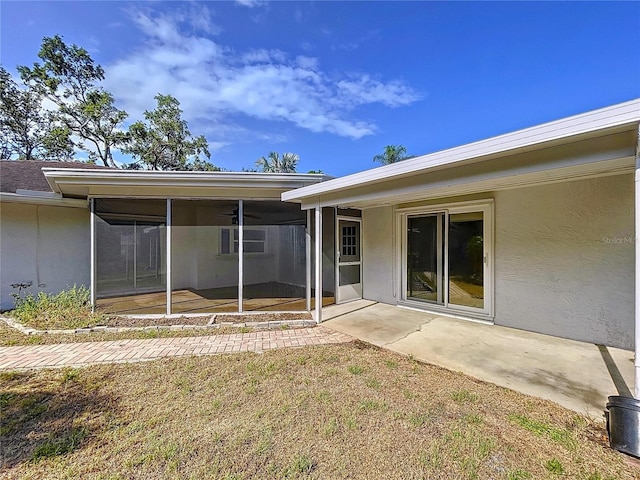 13725 Oak Forest Blvd N, Seminole, FL 33776 - rear view of house featuring a sunroom, a patio area, a ceiling fan, and stucco siding