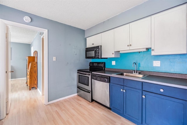 8220 12th Way N Unit G, Saint Petersburg, FL 33702 - kitchen with appliances with stainless steel finishes, a sink, blue cabinets, a textured ceiling, and light wood-type flooring