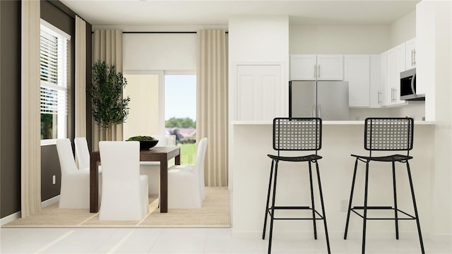 234 SE 27th St, Ruskin, FL 33570 - kitchen featuring freestanding refrigerator, stainless steel microwave, a kitchen breakfast bar, and healthy amount of natural light