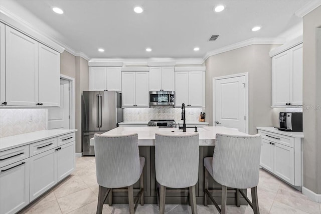32193 Watoga Loop, Wesley Chapel, FL 33543 - kitchen with appliances with stainless steel finishes, a kitchen breakfast bar, a kitchen island with sink, decorative backsplash, and ornamental molding