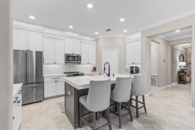32193 Watoga Loop, Wesley Chapel, FL 33543 - kitchen featuring appliances with stainless steel finishes, light countertops, ornamental molding, a kitchen island with sink, and recessed lighting