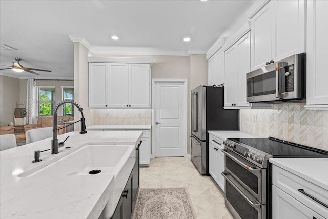 32193 Watoga Loop, Wesley Chapel, FL 33543 - kitchen with stainless steel appliances, crown molding, a ceiling fan, backsplash, and white cabinets