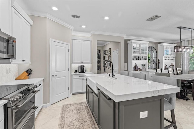 32193 Watoga Loop, Wesley Chapel, FL 33543 - kitchen with stainless steel appliances, white cabinets, crown molding, a breakfast bar area, and an island with sink