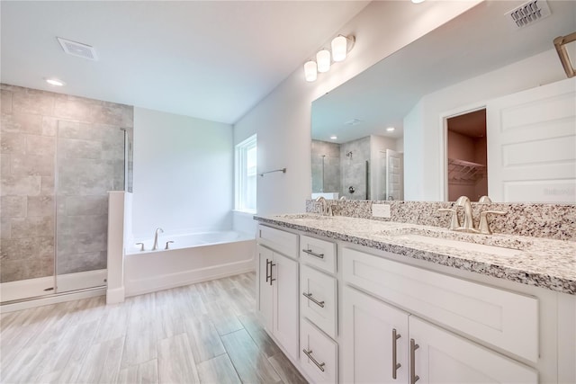 16508 66th Ln E, Parrish, FL 34219 - full bath with a stall shower, double vanity, a bath, a walk in closet, and wood finished floors